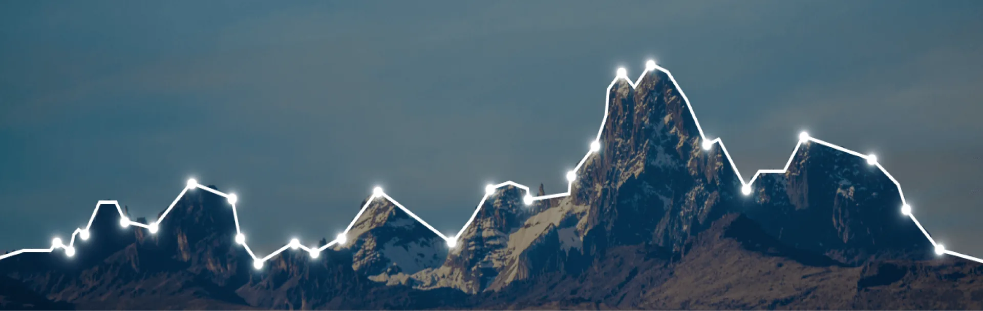 A group of snow-covered mountains. The landscape features a cloudy sky and a glacial terrain.